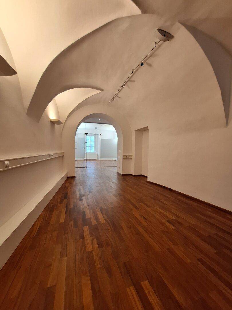 Langer Flur mit eleganten Gewölbedecken und Holzboden, der zu weiteren Räumen führt.