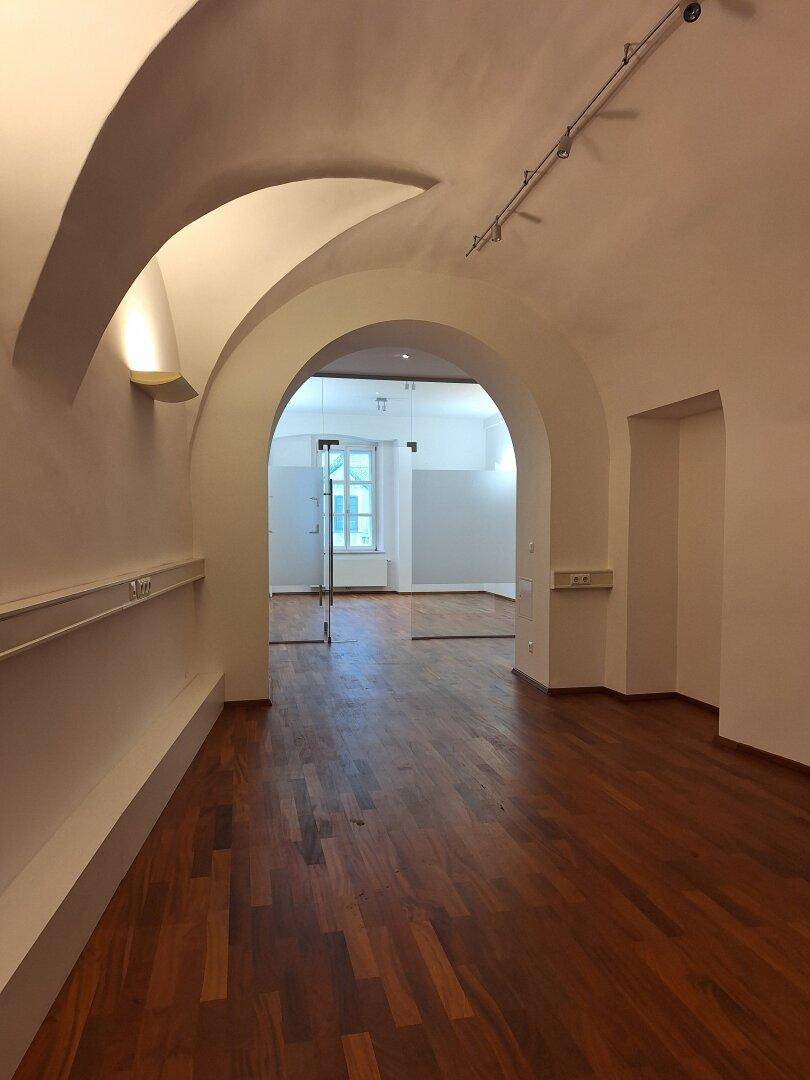 Langer Flur mit eleganten Gewölbedecken und Holzboden, der zu weiteren Räumen führt.