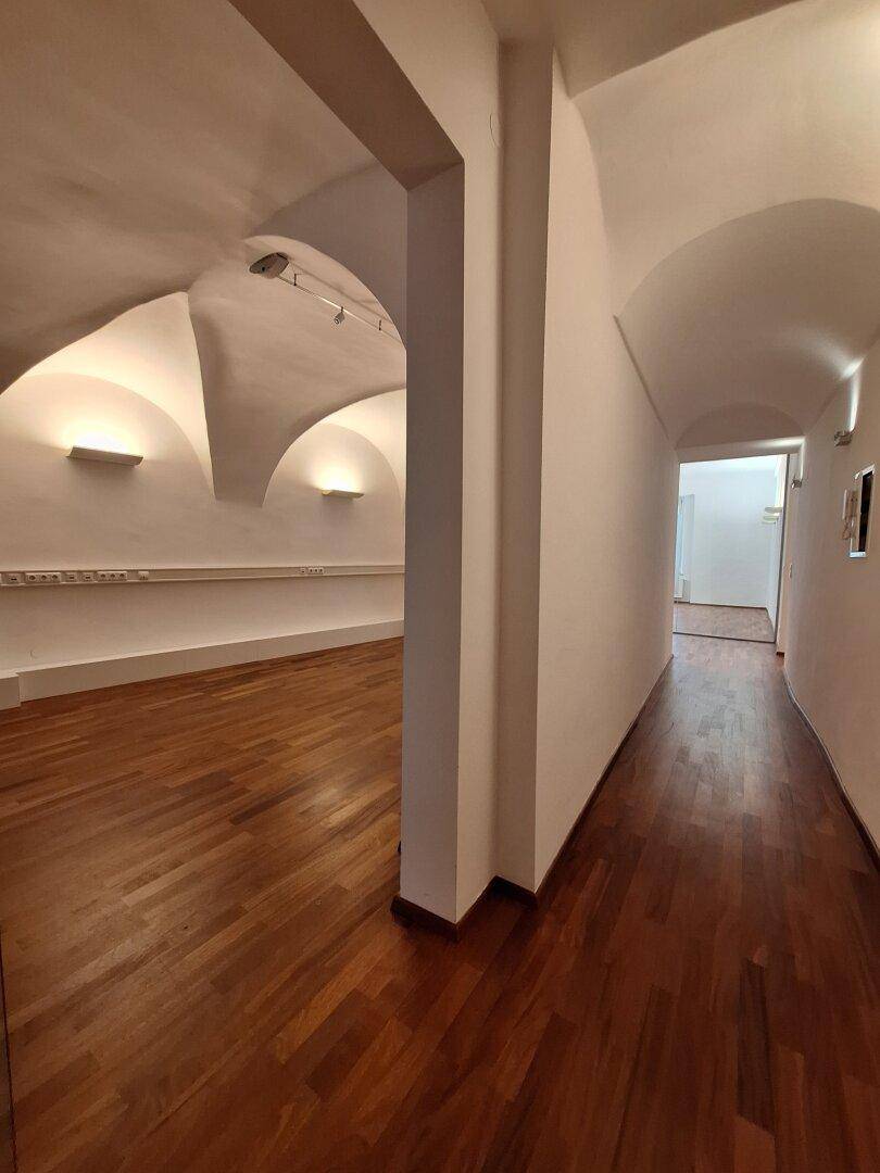 Langer Flur mit eleganten Gewölbedecken und Holzboden, der zu weiteren Räumen führt.