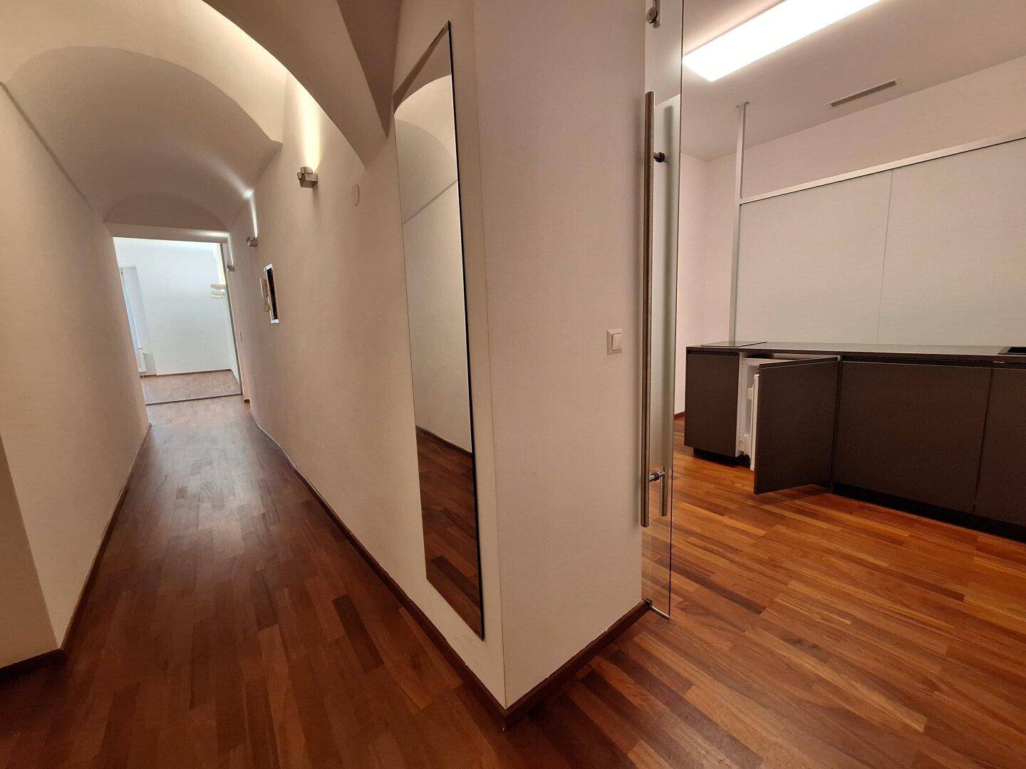 Heller Flur mit Holzboden und einem großen Spiegel, der den historischen Charme des Gebäudes unterstreicht.
