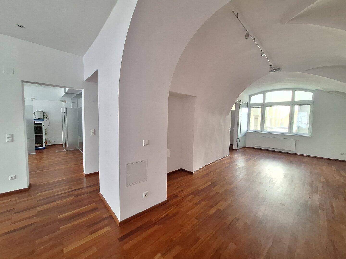 Großer Büroraum mit beeindruckenden Gewölbedecken und großen Fenstern, die viel Tageslicht hereinlassen.