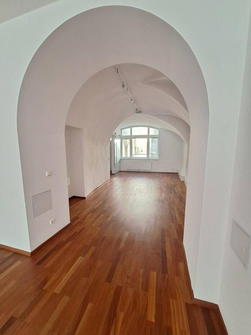 Heller Büroraum mit Holzboden und großen Fenstern, die für viel Tageslicht sorgen.