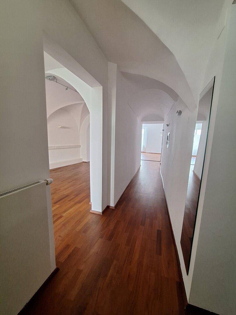 Heller Büroraum mit Holzboden und großen Fenstern, die für viel Tageslicht sorgen.