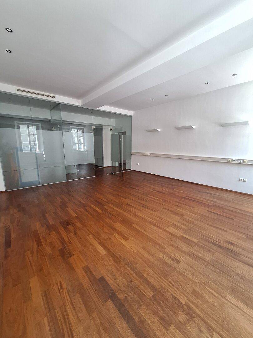 Heller Büroraum mit Holzboden und großen Fenstern, die für viel Tageslicht sorgen.