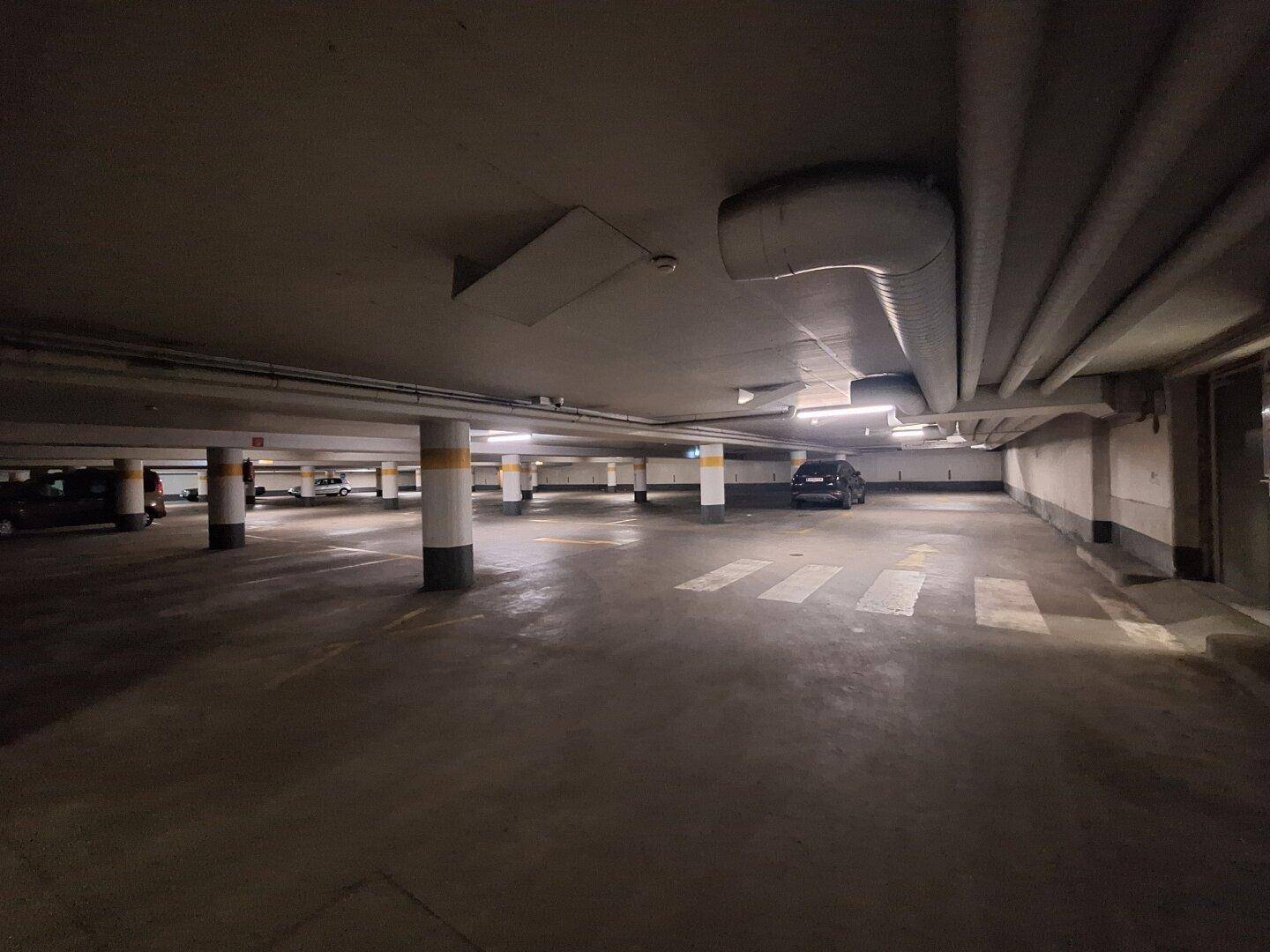Weitläufige Tiefgarage mit vielen Stellplätzen, Säulen und guter Beleuchtung.