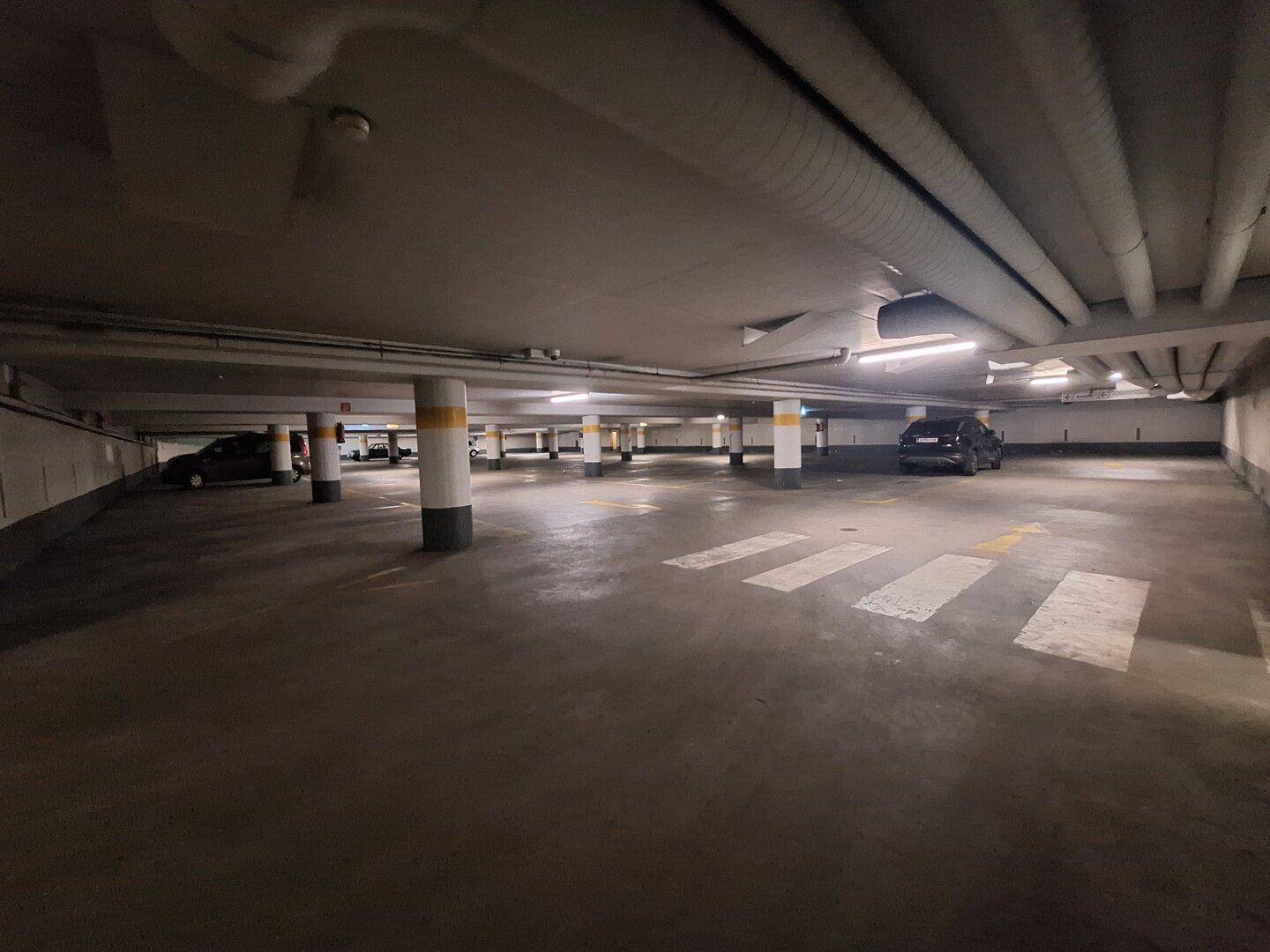 Große Tiefgarage mit vielen Stellplätzen, Säulen und guter Beleuchtung, bereit zur Nutzung.