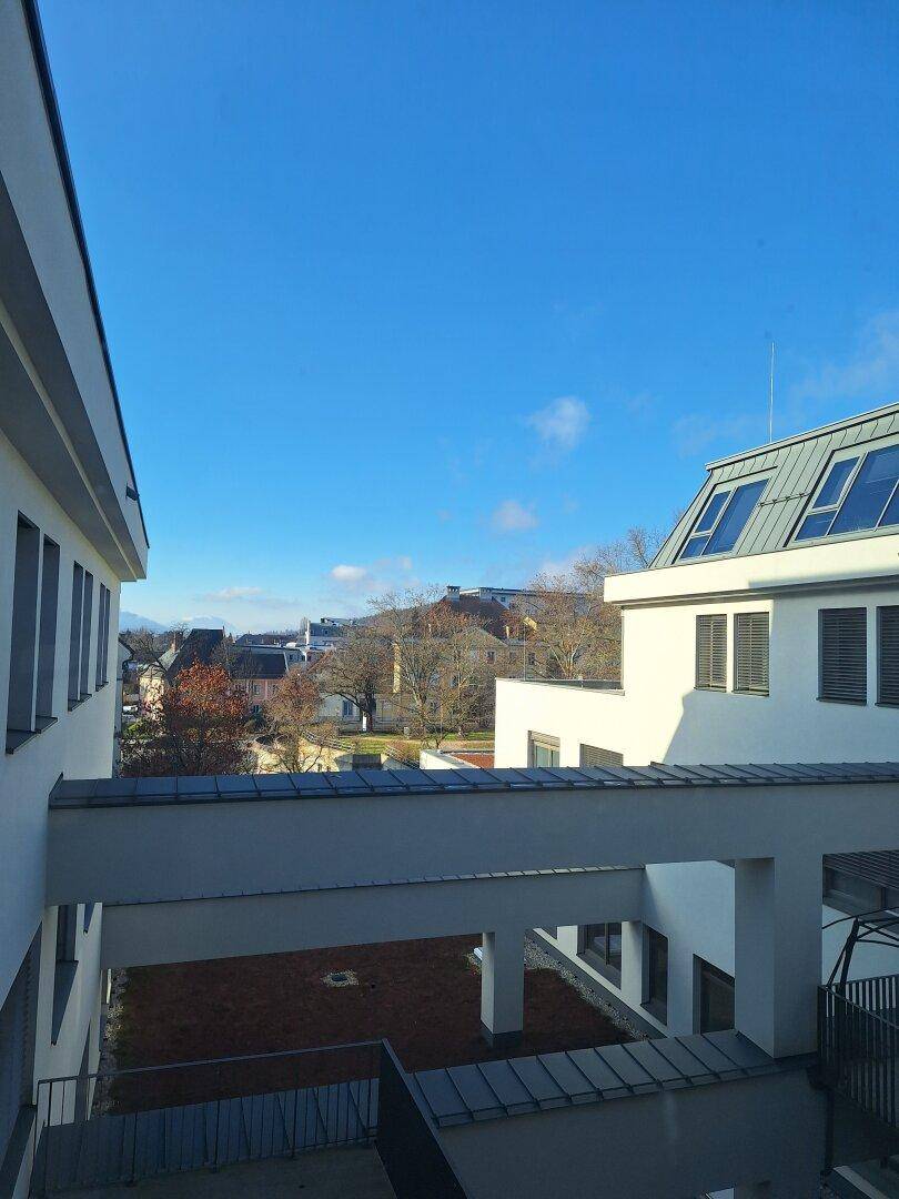 Blick zwischen modernen Gebäuden auf die umliegende Landschaft und den blauen Himmel.