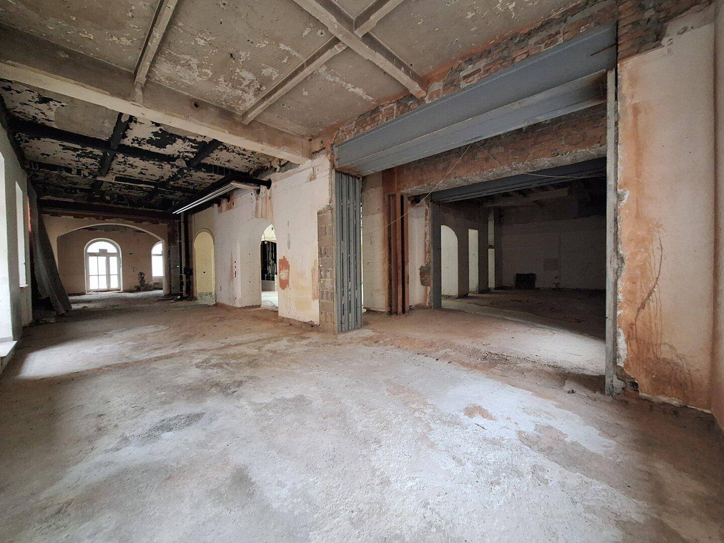 Innenraum in Renovierung mit freigelegten Wänden und Säulen, der das Potenzial für eine offene Raumgestaltung zeigt.