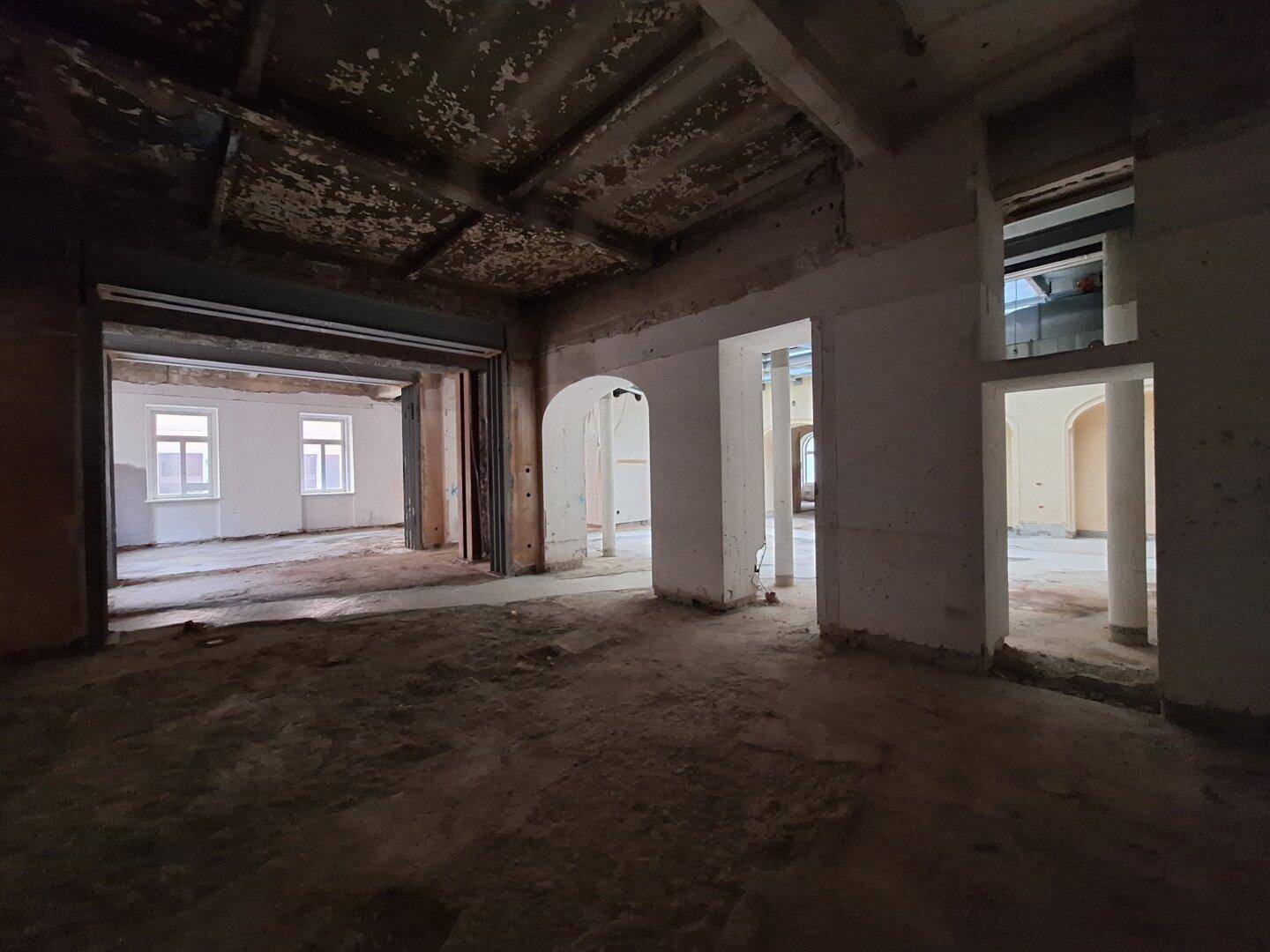 Innenraum in Renovierung mit freigelegten Wänden und Säulen, der das Potenzial für eine offene Raumgestaltung zeigt.