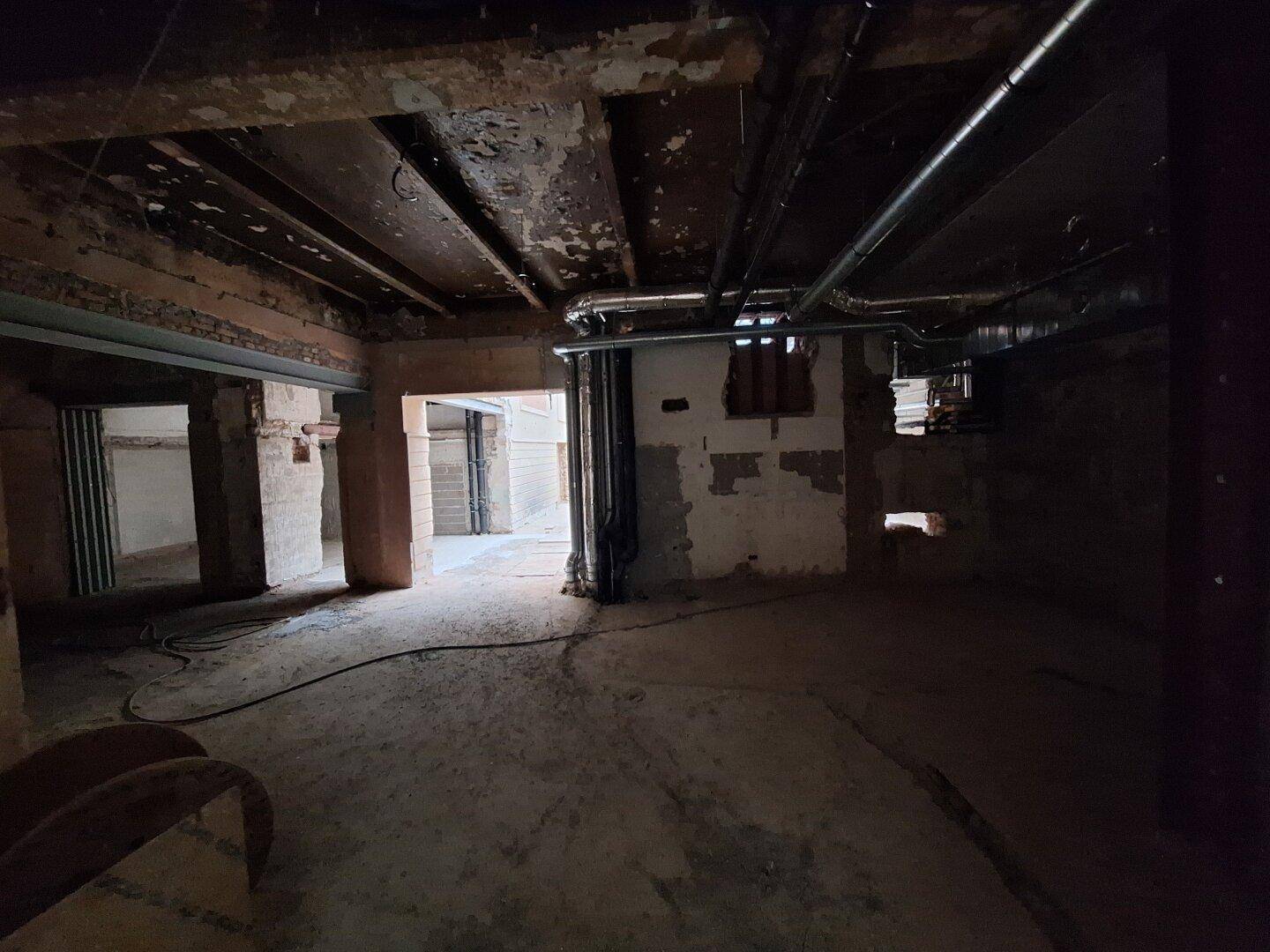 Dunklerer Innenraum in Renovierung mit sichtbaren Rohren und freigelegten Wänden, der auf eine umfassende Sanierung hindeutet.
