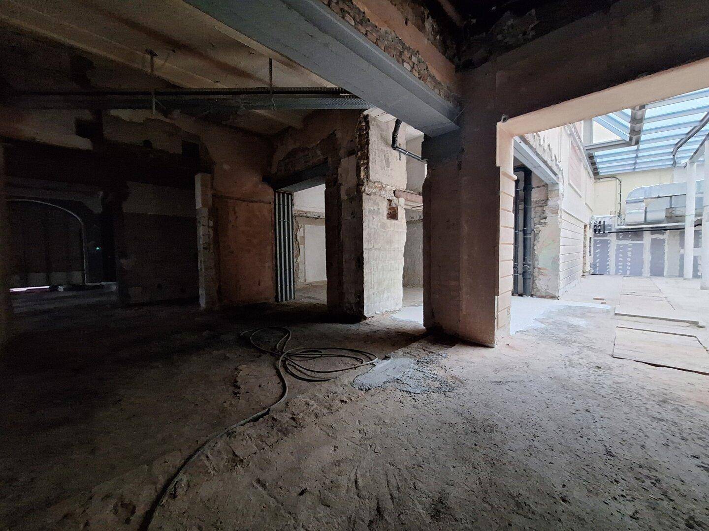 Innenraum in Renovierung mit sichtbaren Rohren und freigelegten Wänden, der auf eine umfassende Sanierung hindeutet.