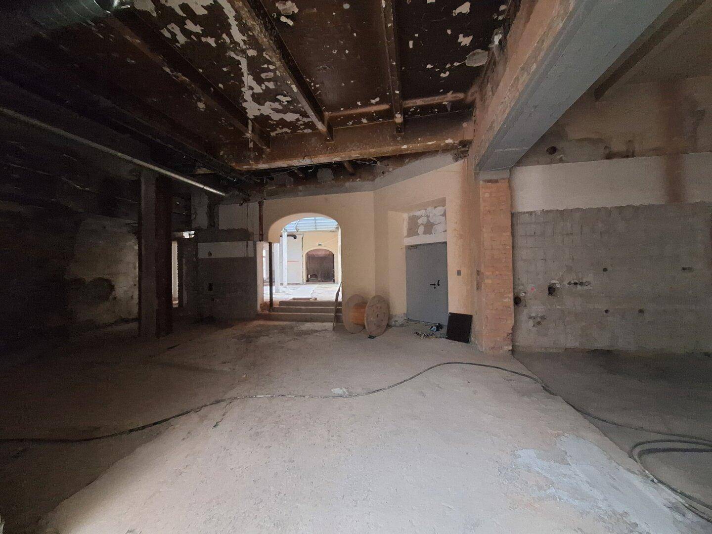 Innenraum in Renovierung mit freigelegten Wänden und einem großen Rundbogen, der das Potenzial für eine offene Raumgestaltung zeigt.