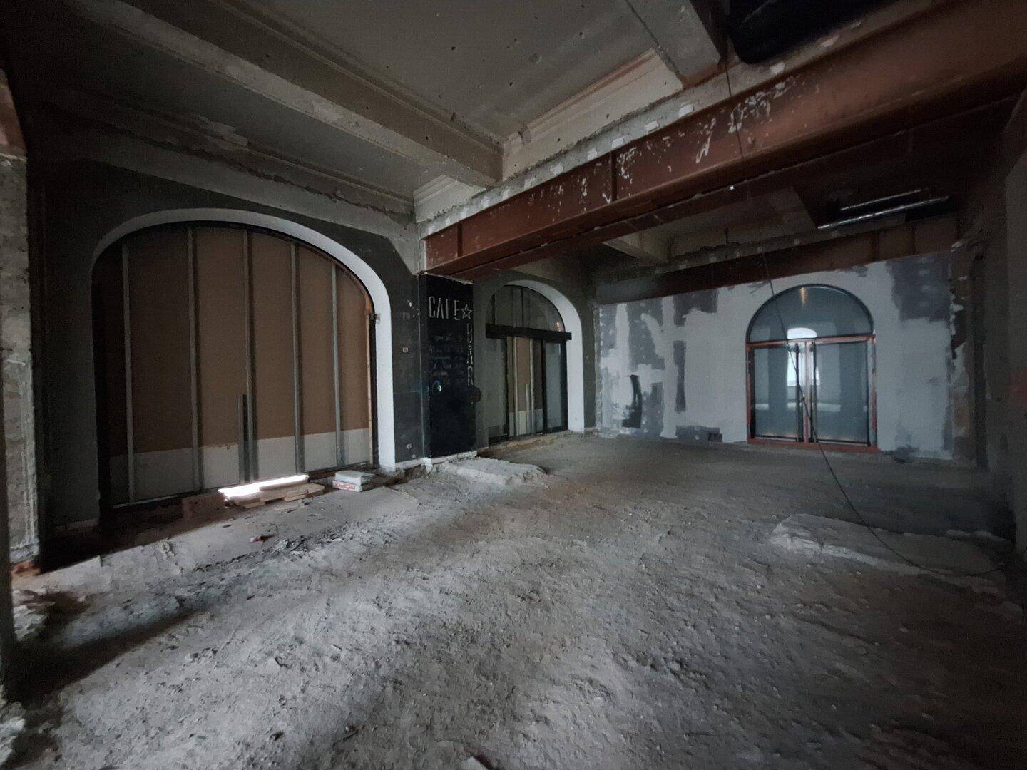 Innenraum in Renovierung mit charakteristischen Rundbögen und sichtbaren Rohbau-Elementen, die auf eine zukünftige Nutzung warten.