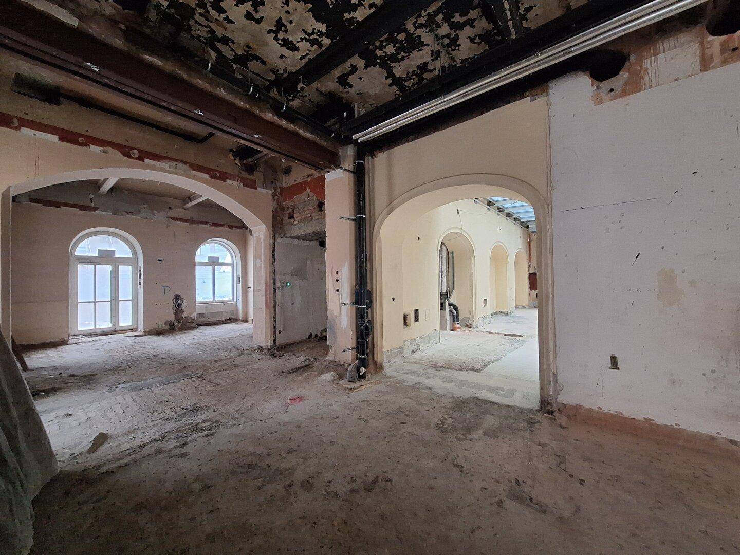 Innenraum in Renovierung mit charakteristischen Rundbögen und sichtbaren Rohbau-Elementen, die auf eine zukünftige Nutzung warten.