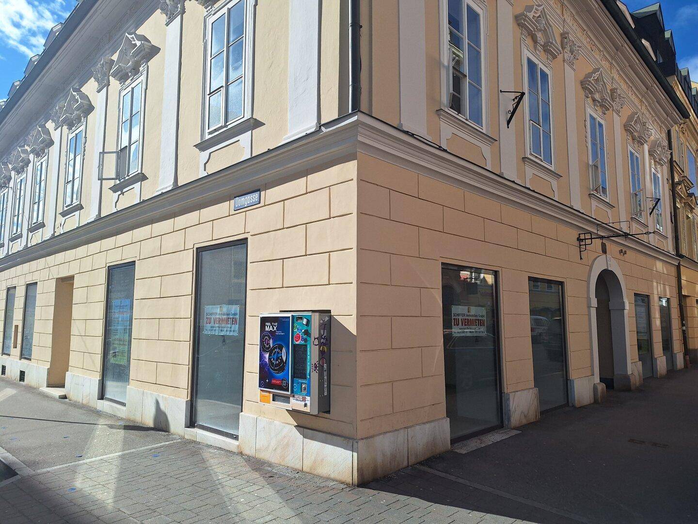 Detailansicht der historischen Fassade mit großen Schaufenstern im Erdgeschoss und dekorativen Elementen.