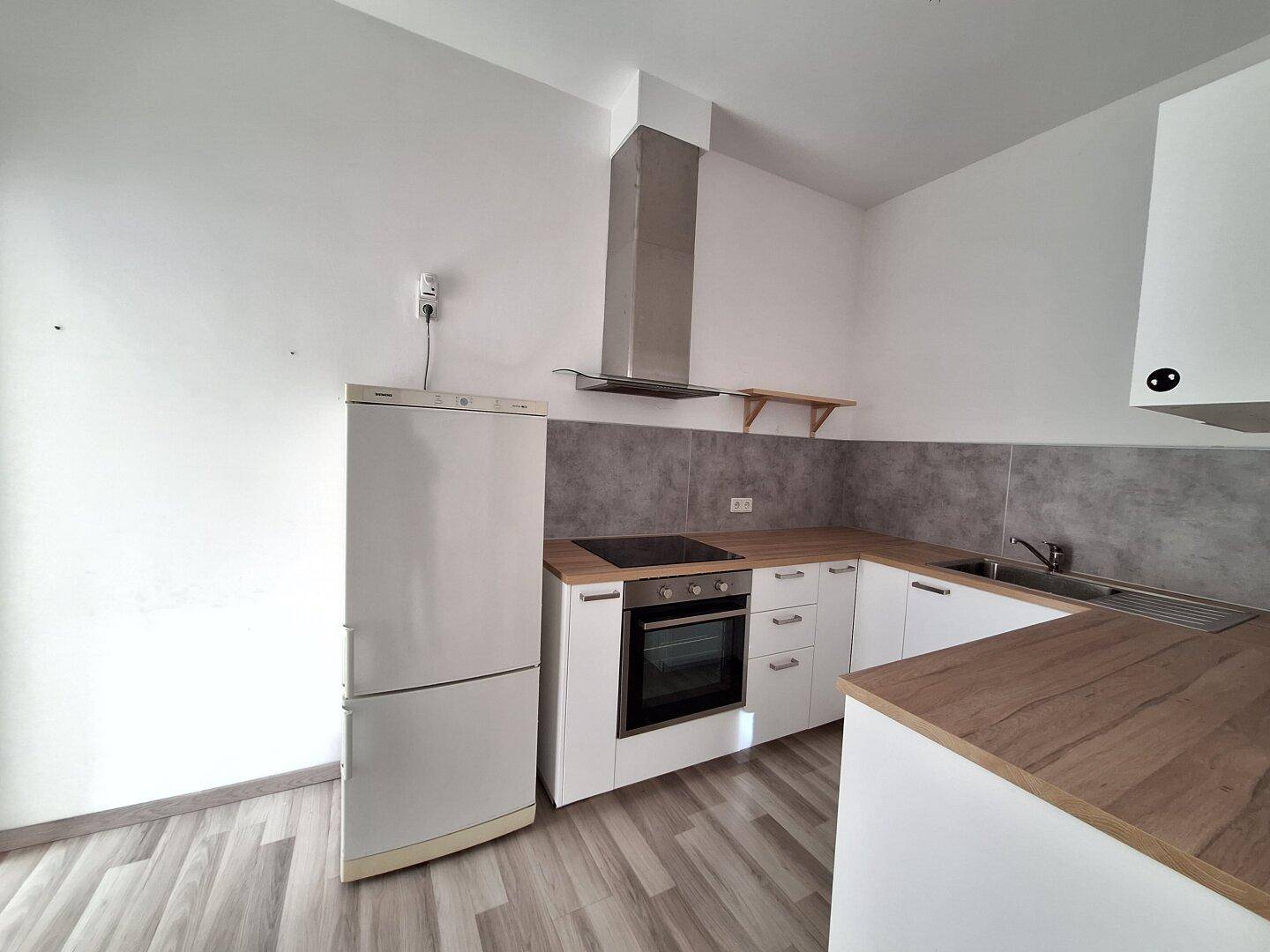 Moderne Küche mit weißer Einrichtung, Holz-Arbeitsplatte und Dunstabzugshaube.
