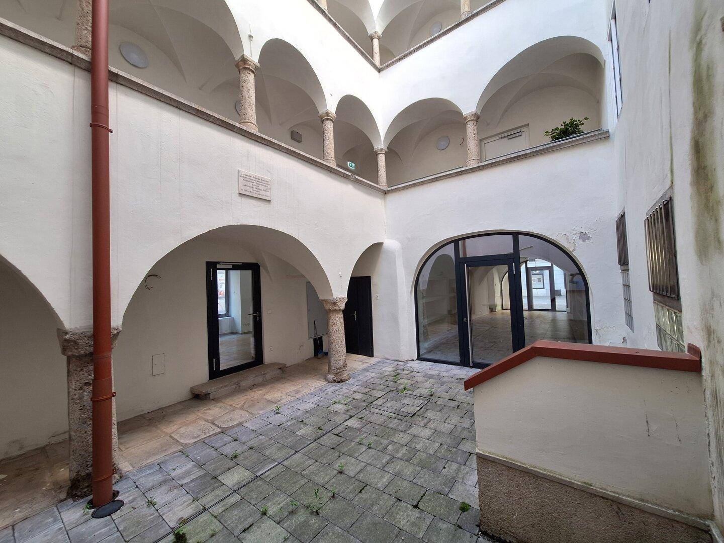 Geräumiger Innenhof mit Arkaden und Säulen, der eine historische Atmosphäre ausstrahlt.