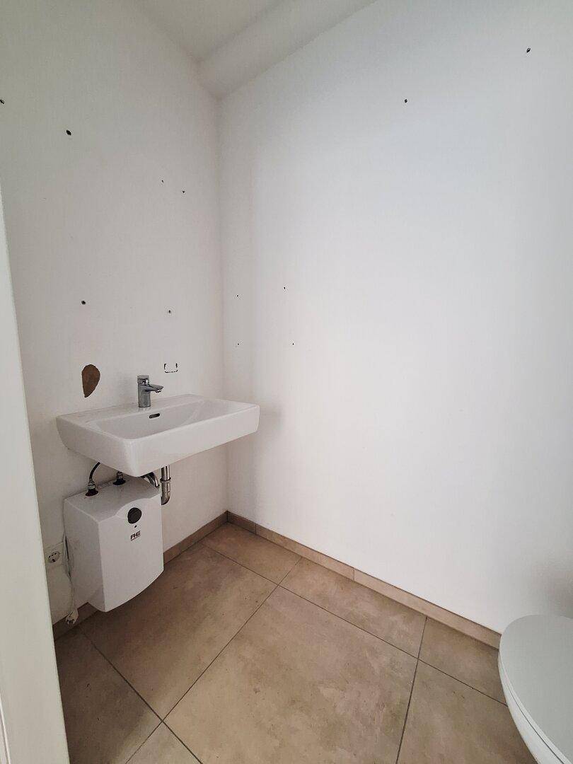 Kleines Gäste-WC mit Waschbecken, Untertischgerät und Fliesenboden, funktional und sauber.