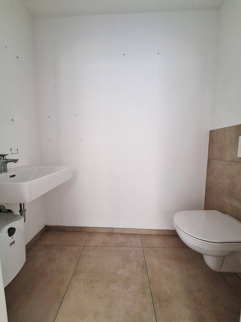 Funktionales Gäste-WC mit Waschbecken, wandhängender Toilette und Fliesenboden, in gutem Zustand.