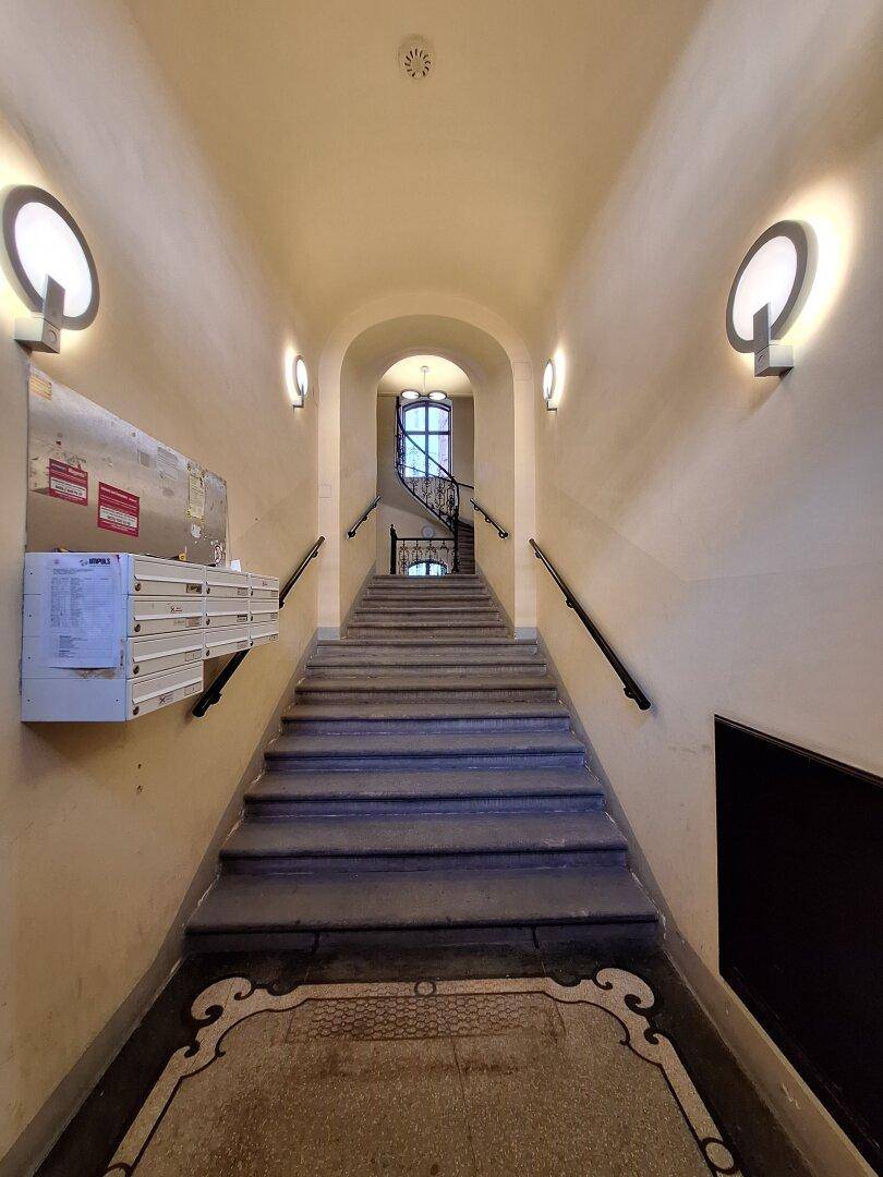 Historisches Treppenhaus mit gewölbter Decke, Briefkästen und dekorativer Beleuchtung.