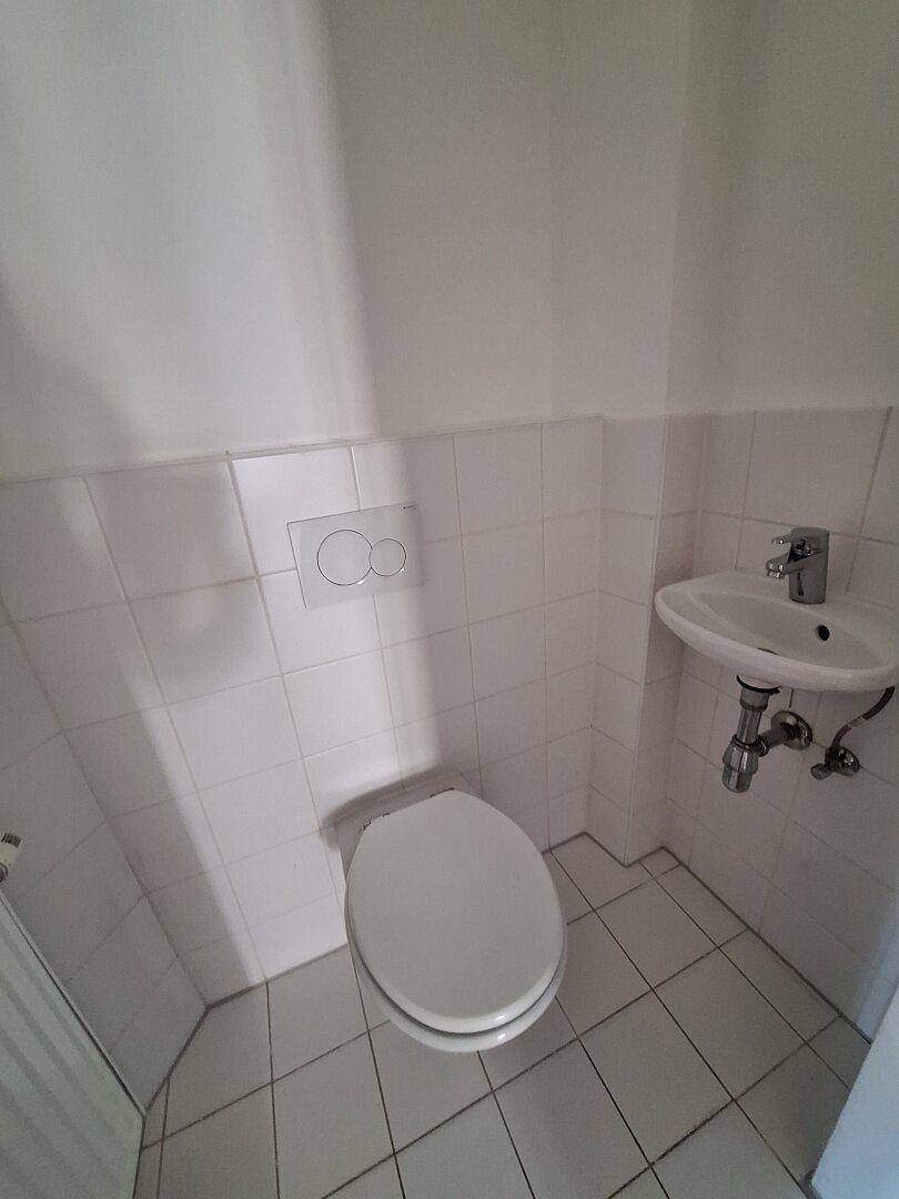 Kleines Gäste-WC mit wandhängender Toilette, Waschbecken und weißen Fliesen.