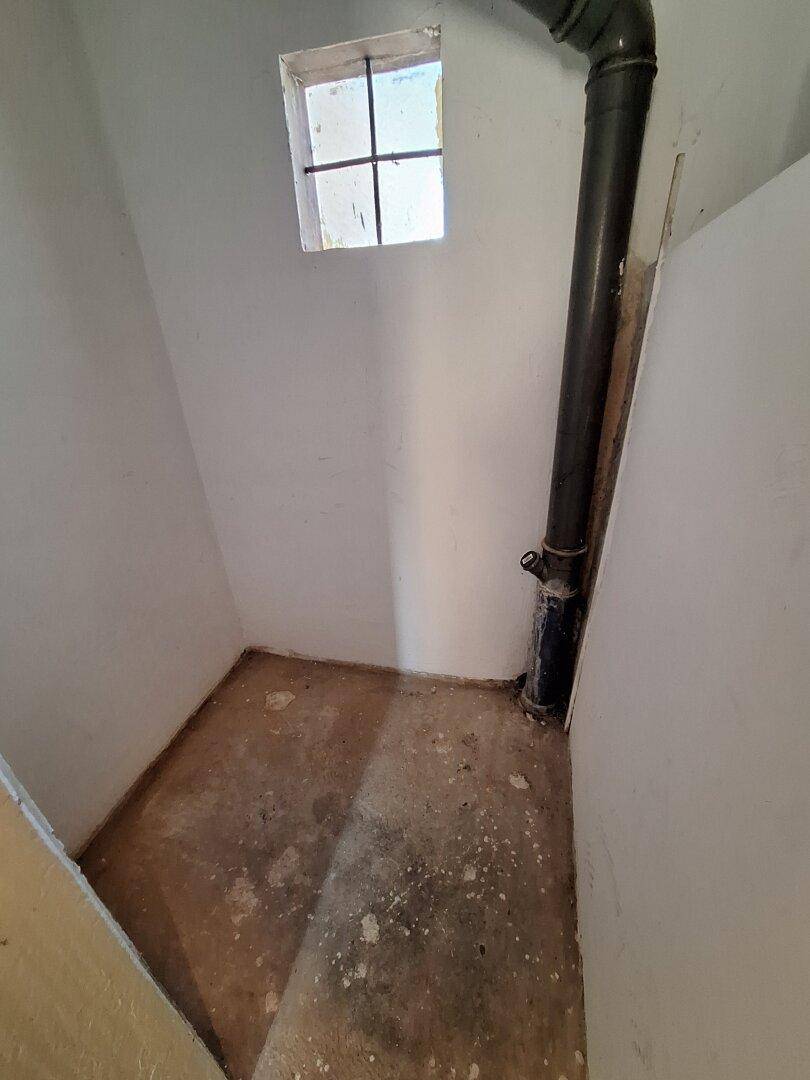 Kleiner Abstellraum mit Fenster und sichtbarem Rohr, der als Lagerfläche dienen könnte.