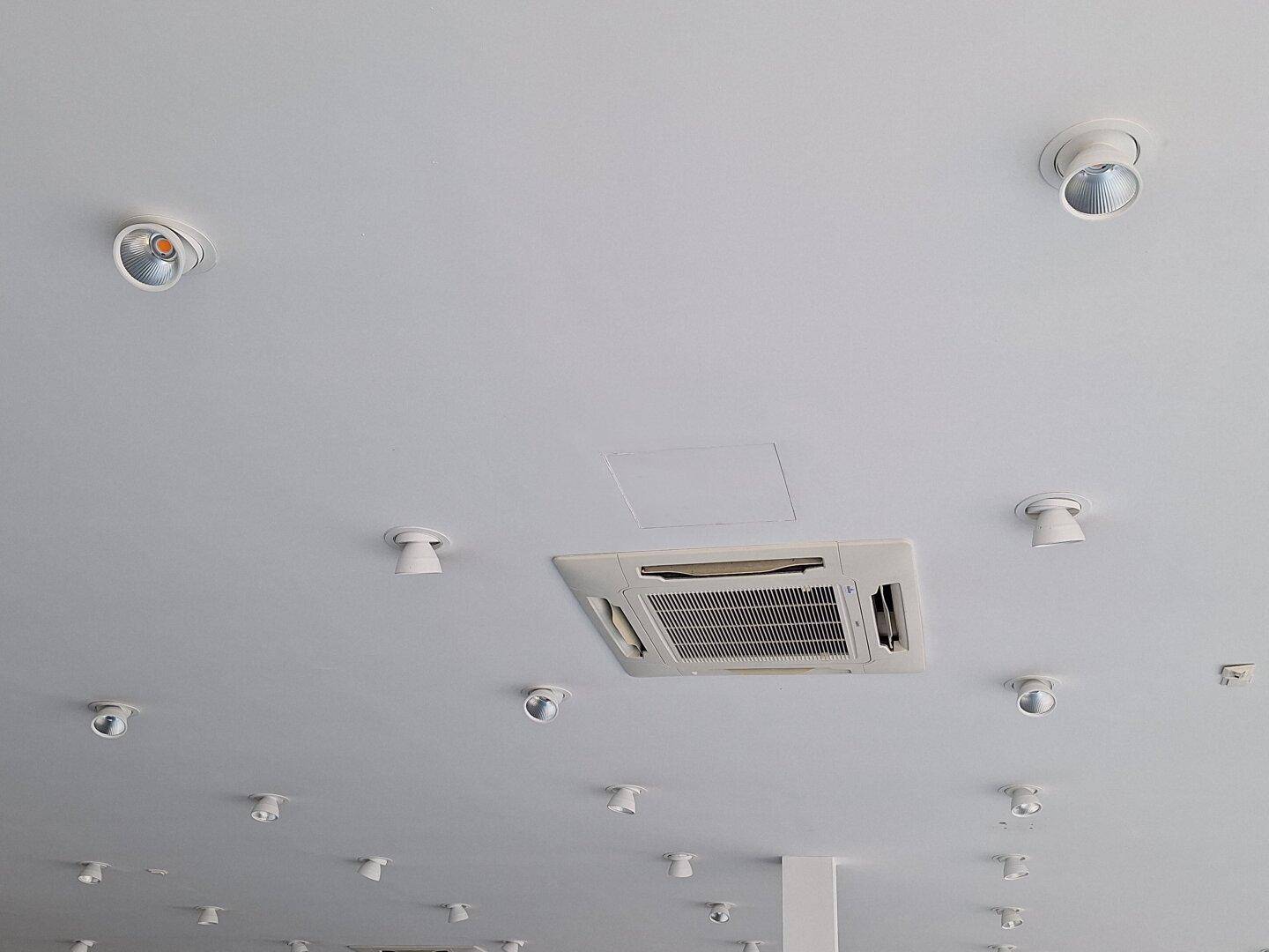 Decke eines Gewerberaums mit zahlreichen Einbaustrahlern und einer zentralen Klimaanlage.