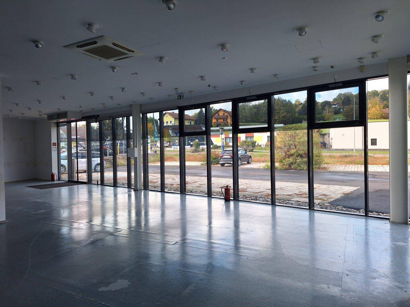 Panoramafensterfront des Gewerberaums bietet eine helle Atmosphäre und direkten Blick auf die Straße und Parkplätze.