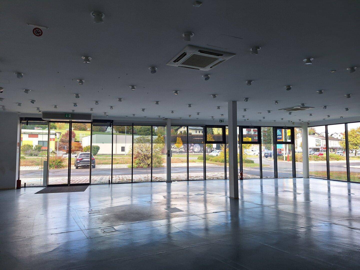 Innenansicht des Gewerberaums mit weitem Blick durch die Glasfront auf den Parkplatz und die Umgebung.