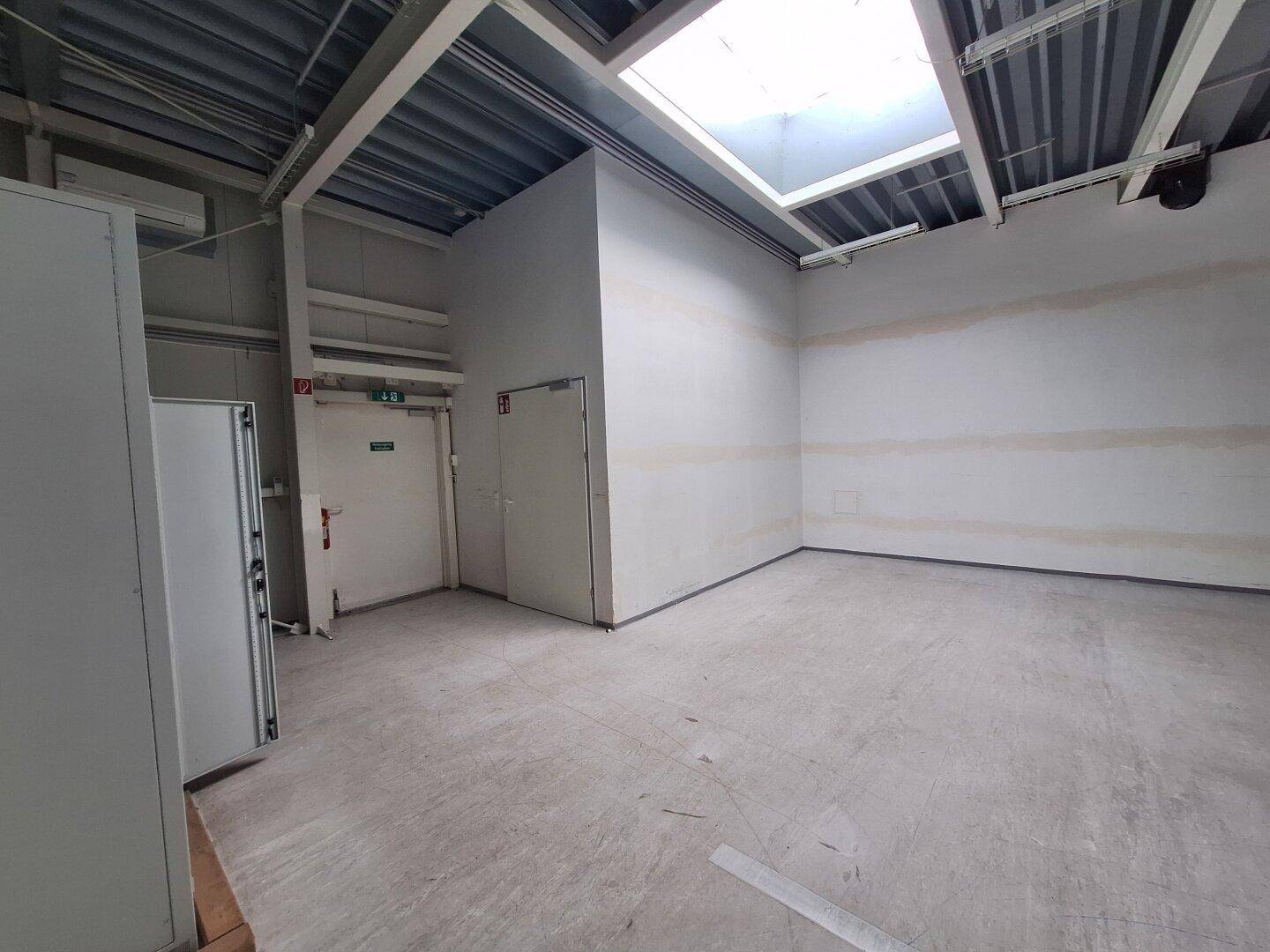 Lagerraum mit sichtbarer Deckenkonstruktion, Oberlicht und zwei Türen, bietet zusätzlichen Stauraum.