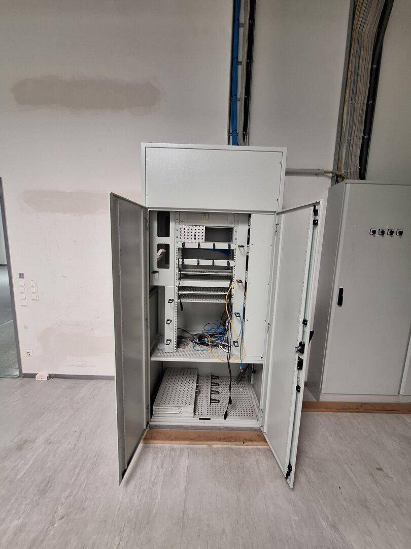 Offener Elektroschrank mit Verkabelung und technischen Installationen in einem Gewerberaum.