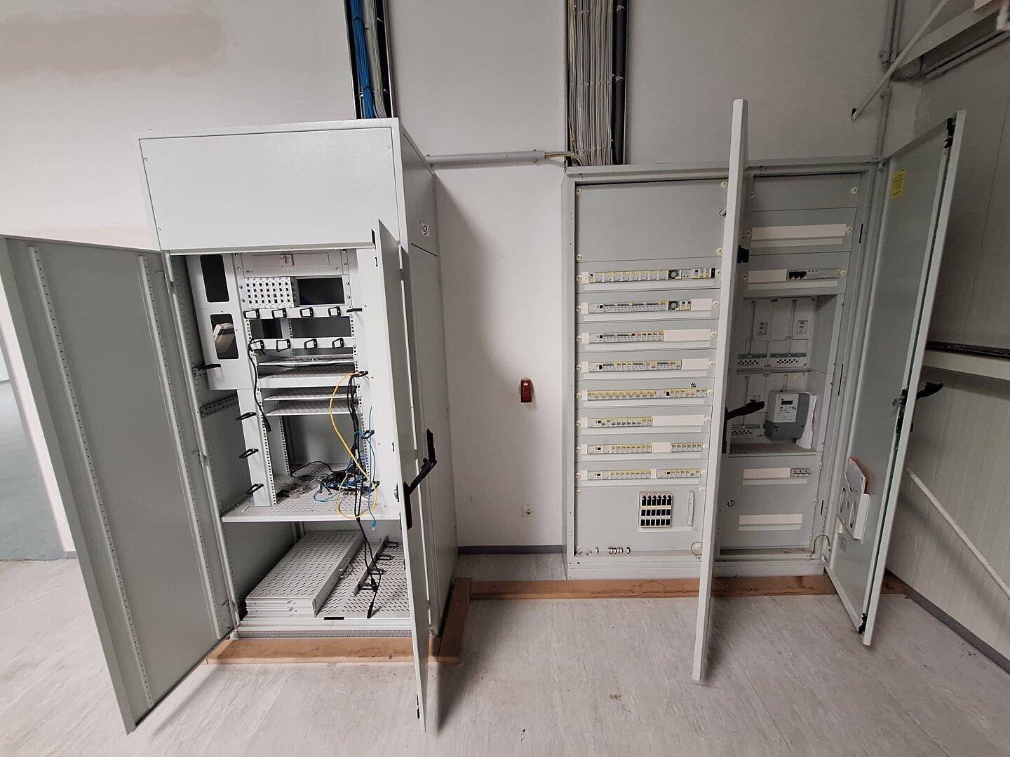 Zwei offene Elektroschränke mit umfangreicher Verkabelung und Sicherungen in einem Technikraum.