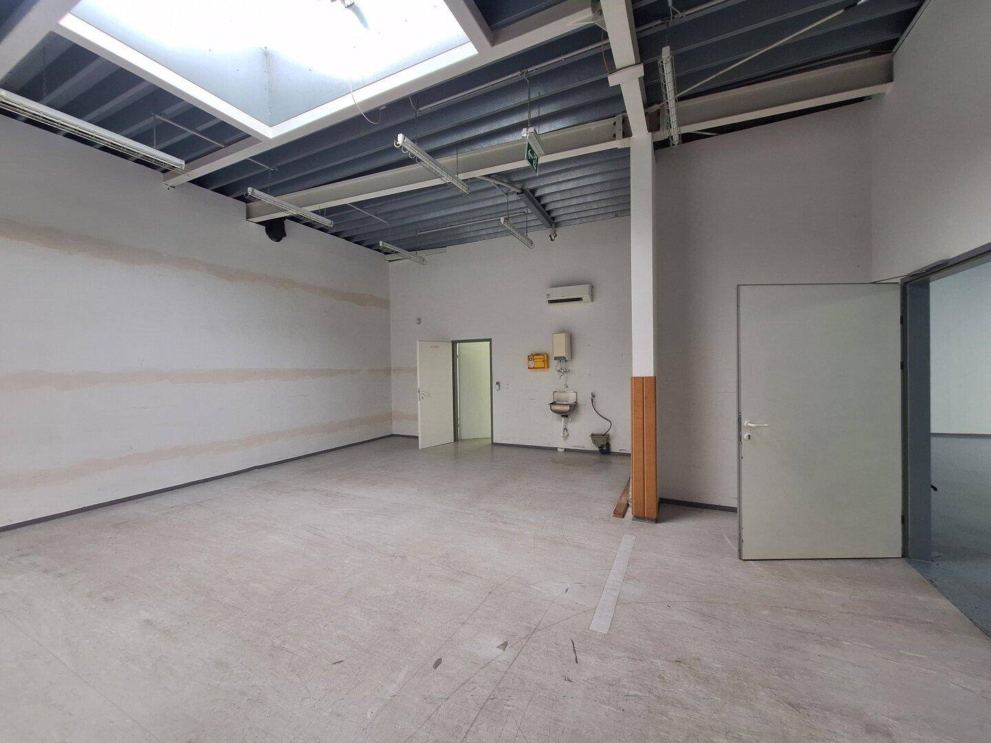 Technikraum mit sichtbarer Deckenkonstruktion, Oberlicht, Klimaanlage und Waschbecken für den Betrieb.