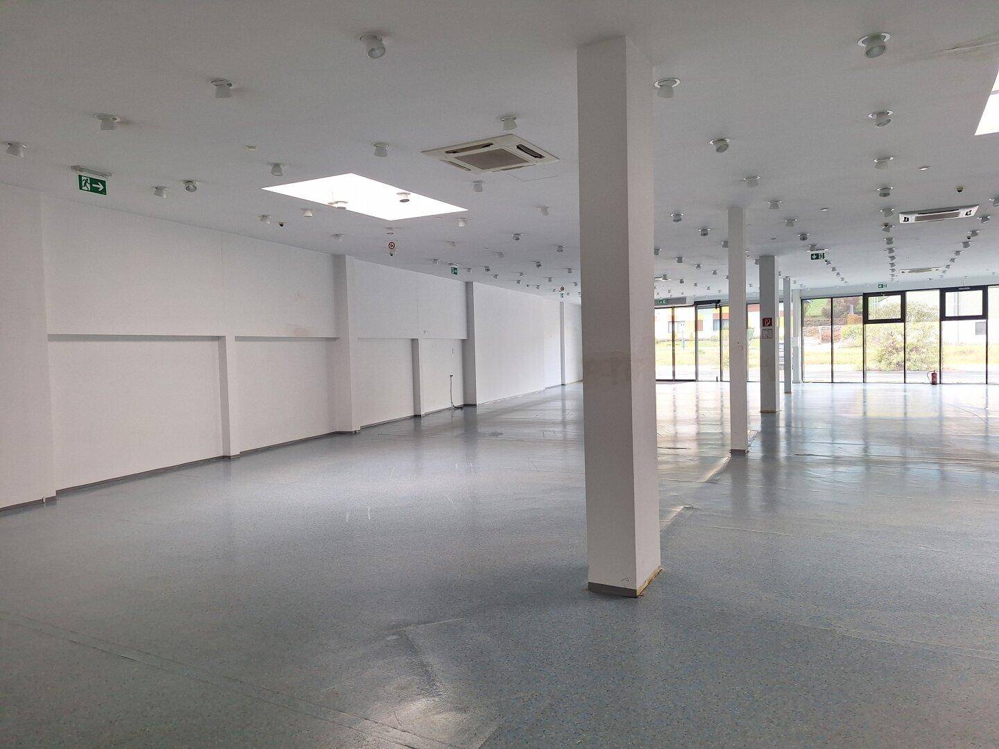 Geräumiger, heller Gewerberaum mit Säulen und großen Fensterfronten, ideal für verschiedene Geschäftskonzepte.