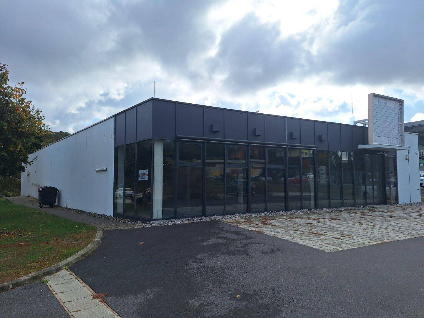 Außenansicht eines modernen Geschäftsgebäudes mit großen Glasfronten und einem Parkplatz.