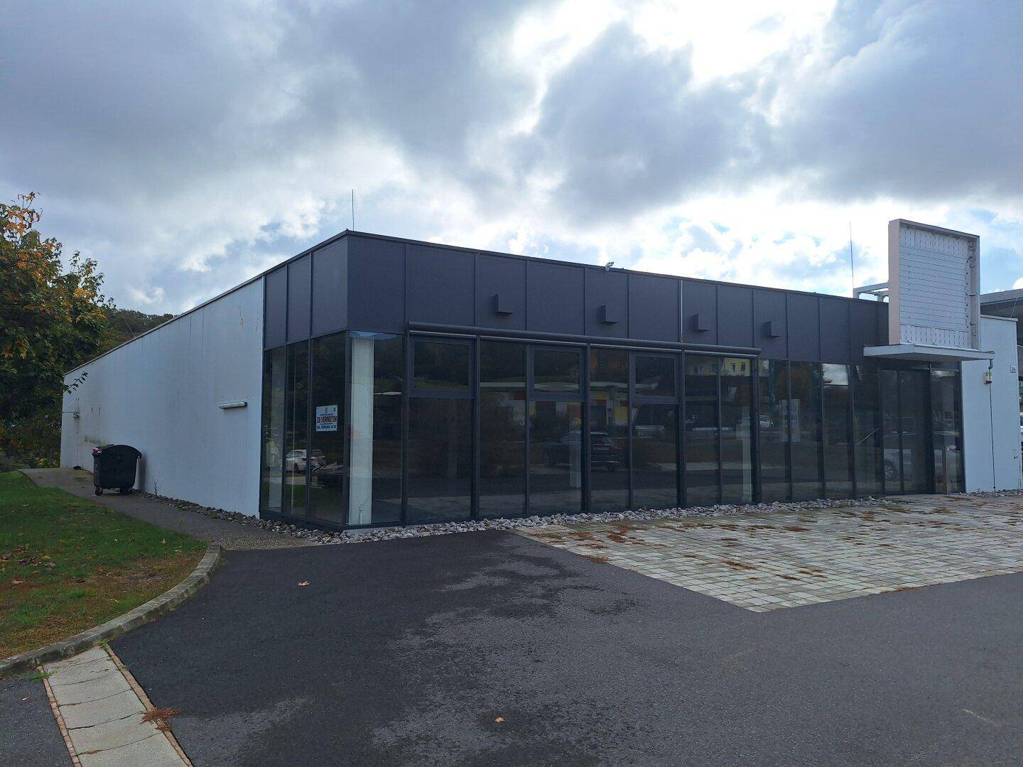 Außenansicht eines modernen Geschäftsgebäudes mit großen Glasfronten und einem Parkplatz.