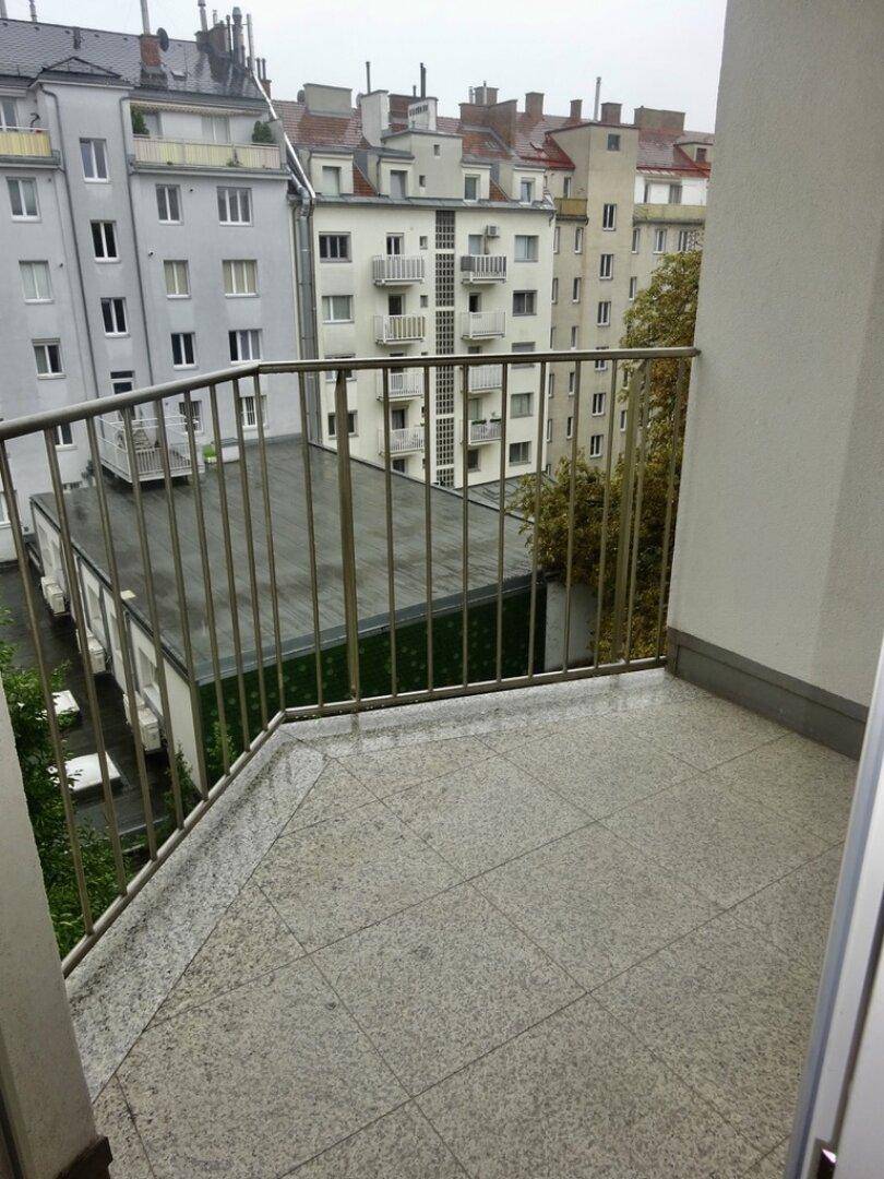 Balkon mit Fliesenboden und weitem Blick über die Dächer der Stadt.