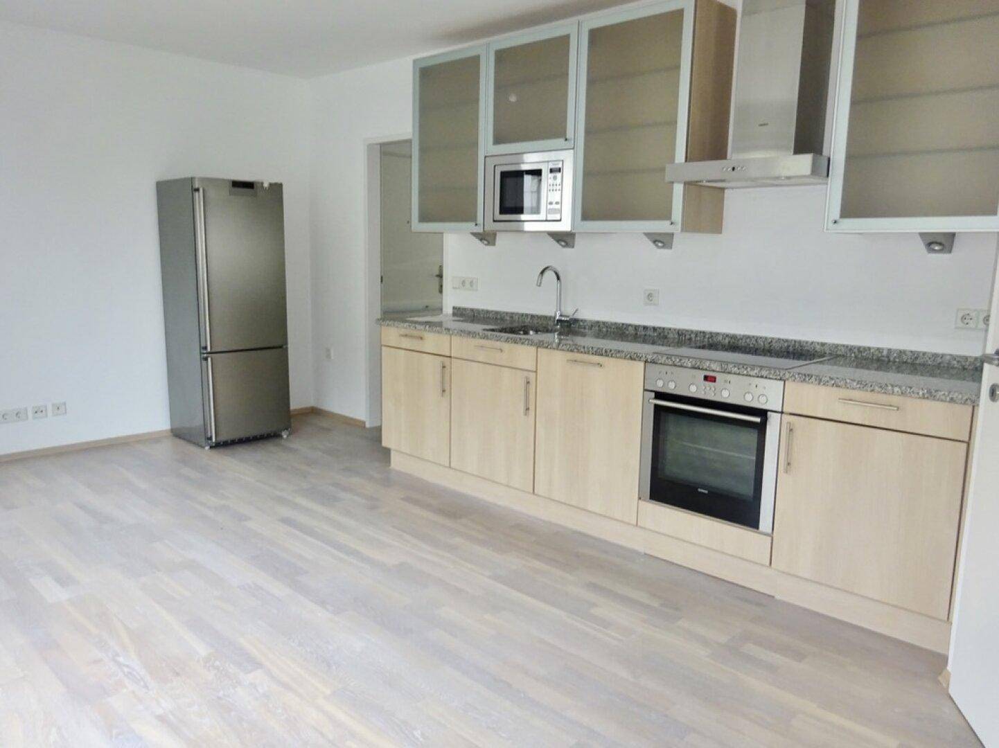 Moderne Einbauküche mit hellen Holzfronten, Granitarbeitsplatte und Edelstahlgeräten.