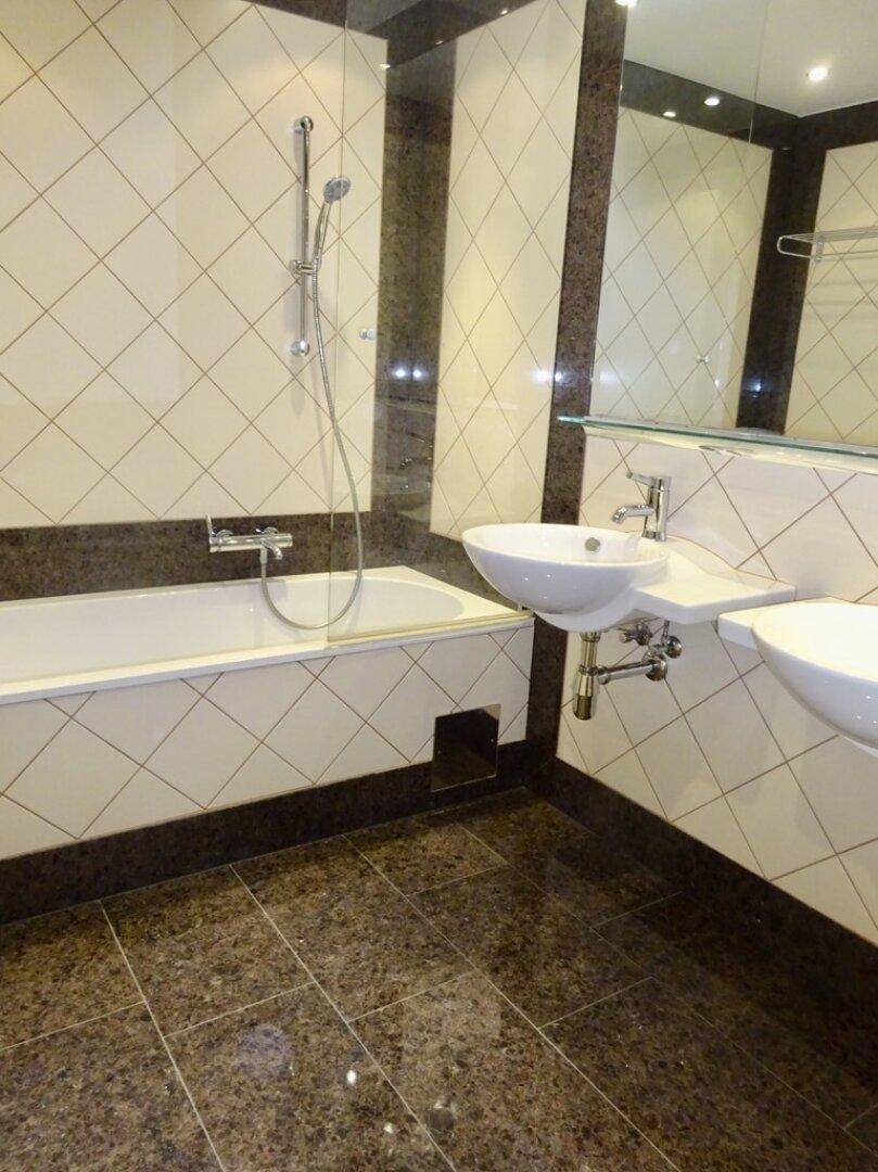 Modernes Badezimmer mit Badewanne, Waschbecken und dunklen Granitfliesen.