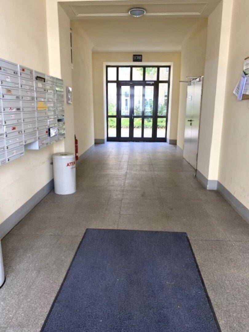 Eingangsbereich eines Gebäudes mit Briefkästen und einer großen Glastür zum Außenbereich.