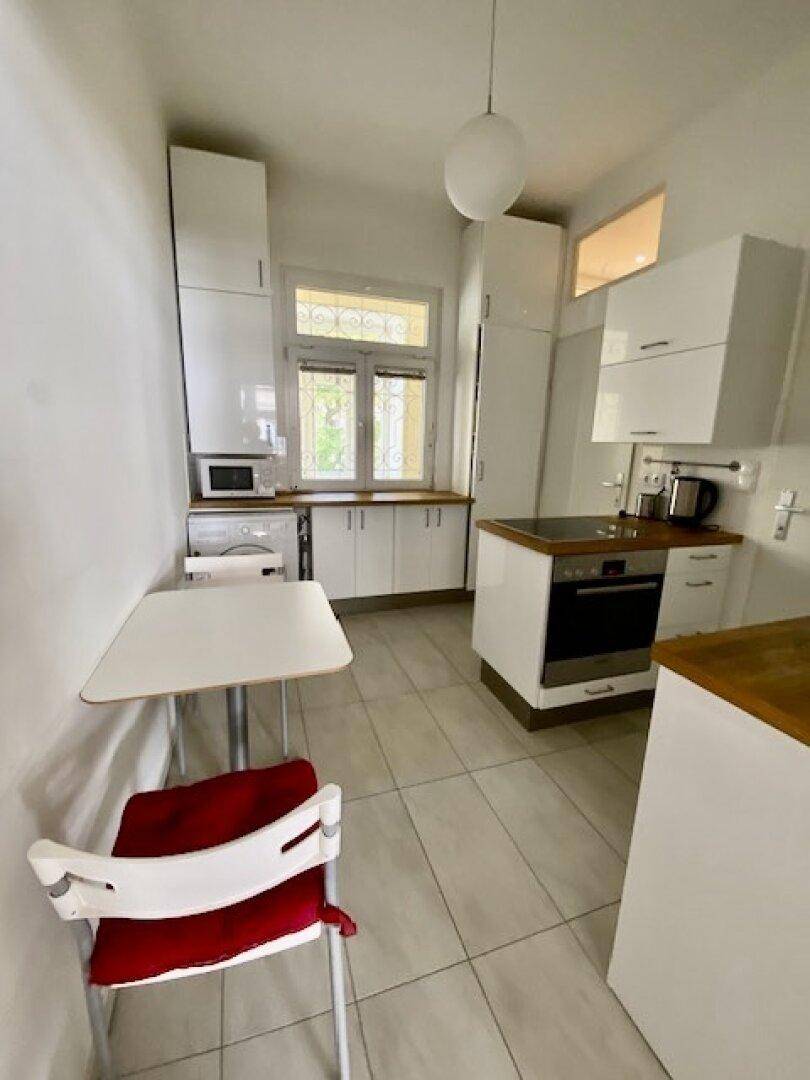 Geräumige Küche mit weißen Schränken, Holzarbeitsplatten und integrierten Küchengeräten.