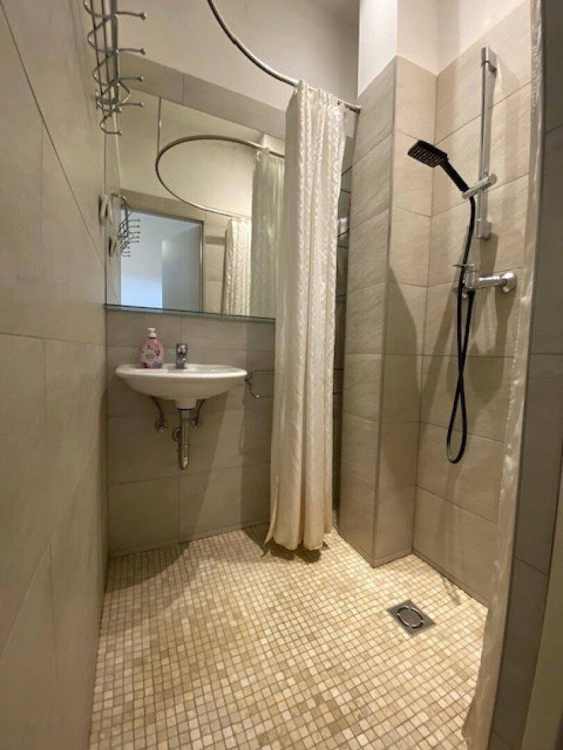 Modernes Badezimmer mit ebenerdiger Dusche, Mosaikfliesen und Waschbecken mit Spiegel.