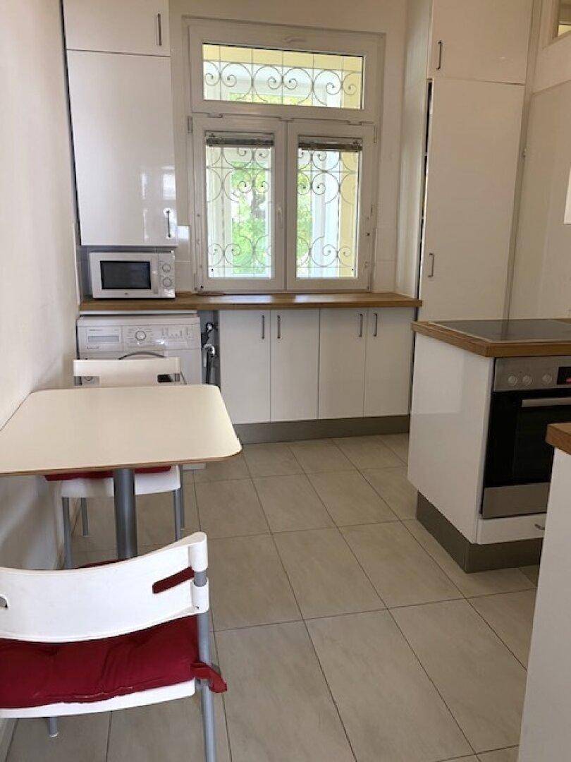 Helle Küche mit weißen Schränken, Holzarbeitsplatten und modernen Geräten, inklusive Waschmaschine.