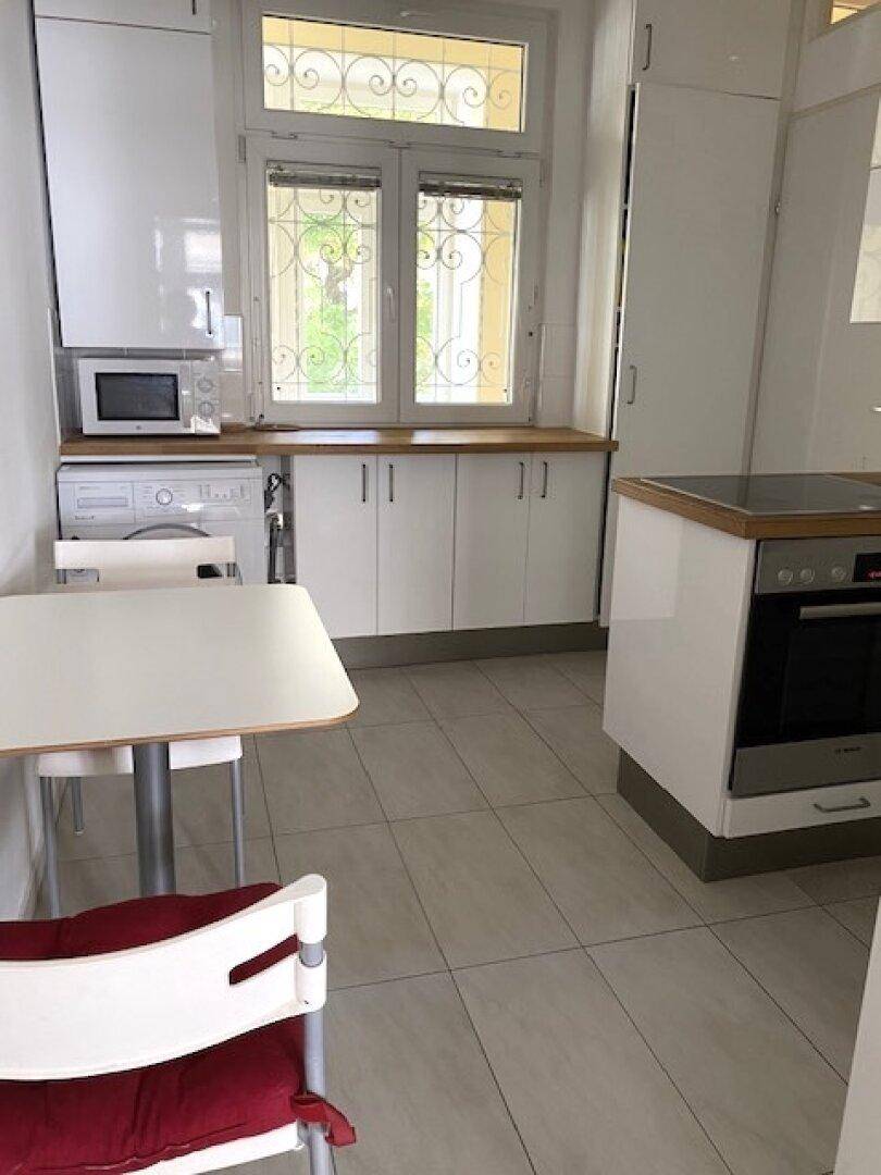 Helle und funktionale Küche mit weißen Schränken, Holzarbeitsplatten und modernen Geräten.