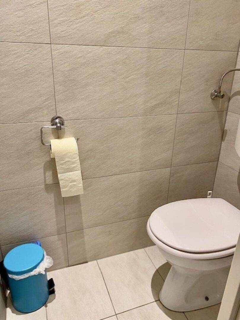 Saubere Toilette mit hellen Fliesen an Wänden und Boden.