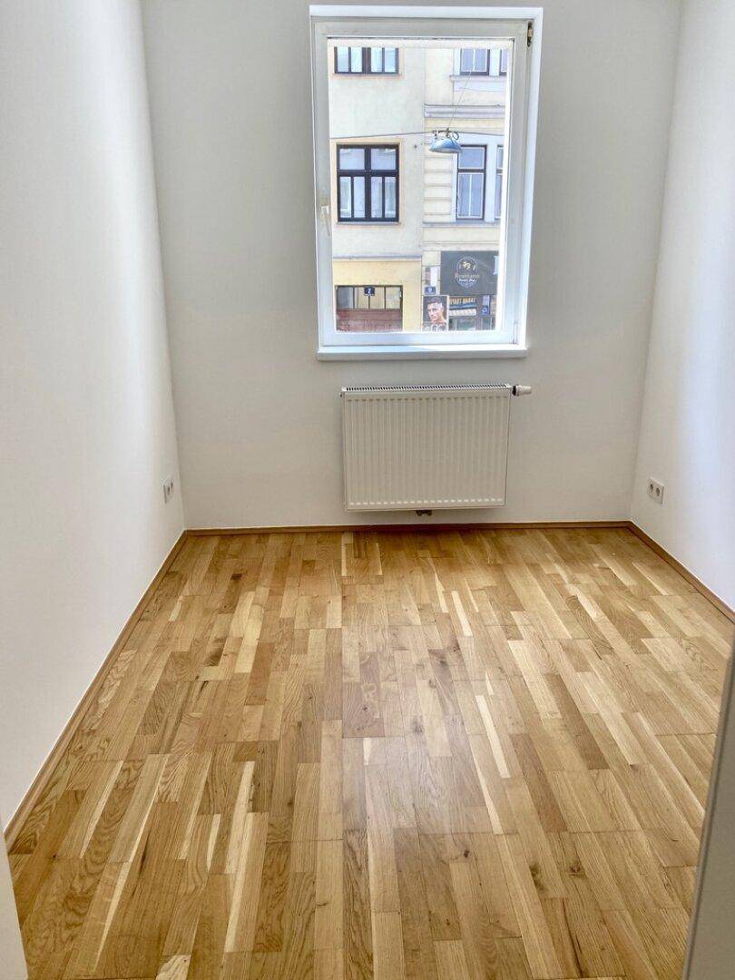 Heller Raum mit Parkettboden und Fenster zur Straßenseite.