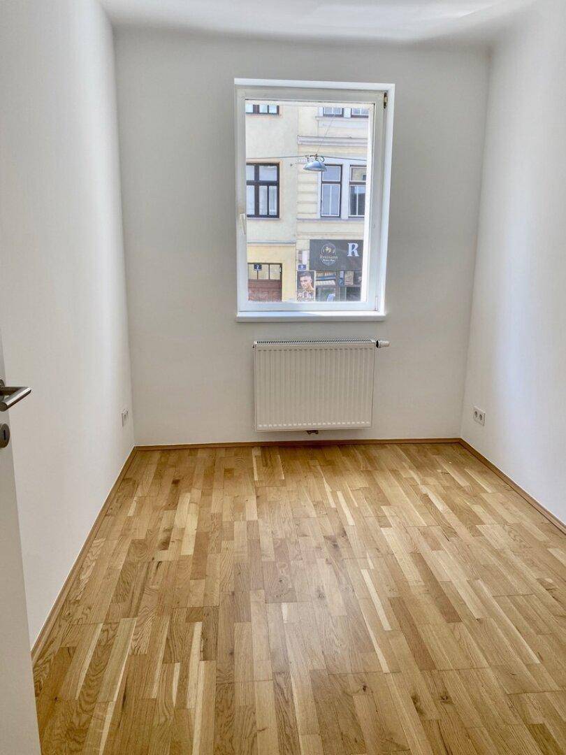 Kleiner Raum mit Parkettboden und Fenster zur Straßenseite.