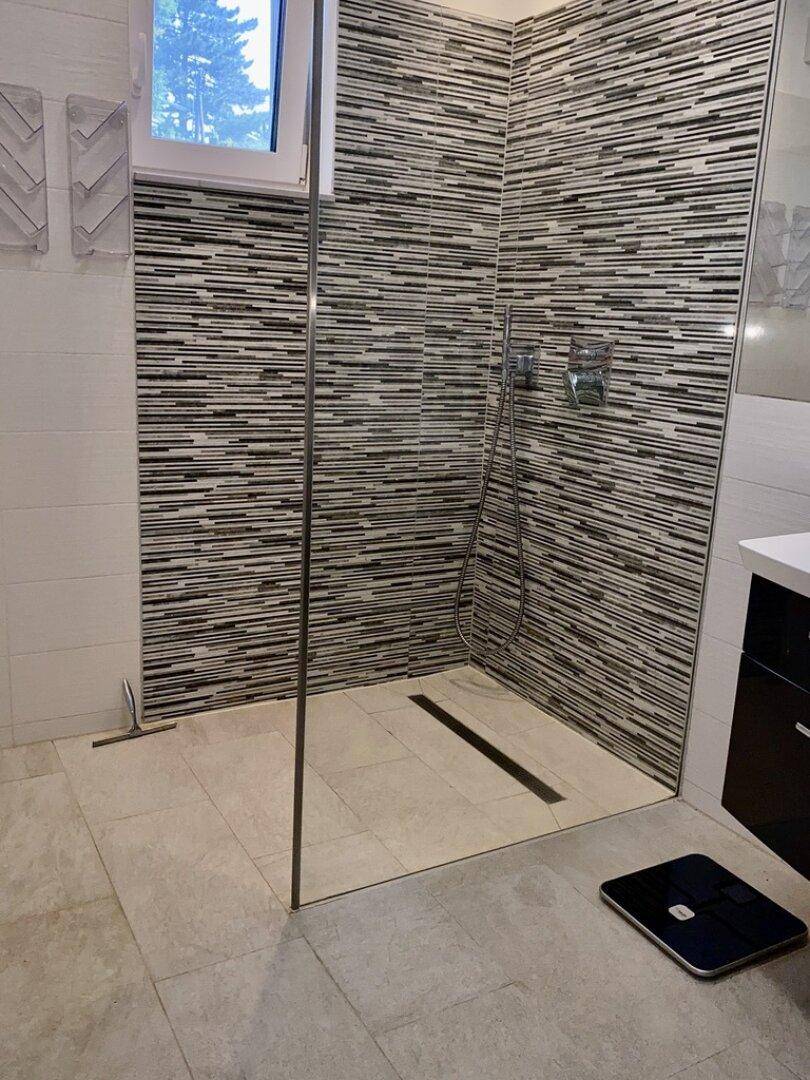 Modernes Badezimmer mit ebenerdiger Dusche, Mosaikfliesen und einem Fenster für Tageslicht.