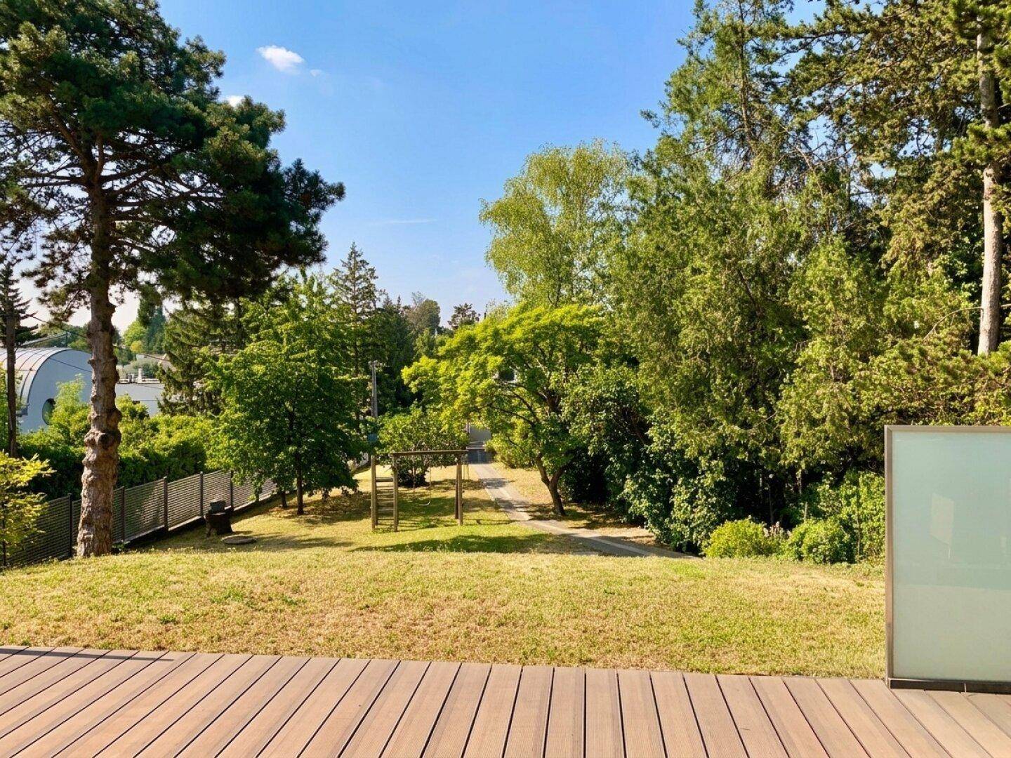 Holzterrasse mit weitem Blick über den grünen Garten und die umliegende Natur.