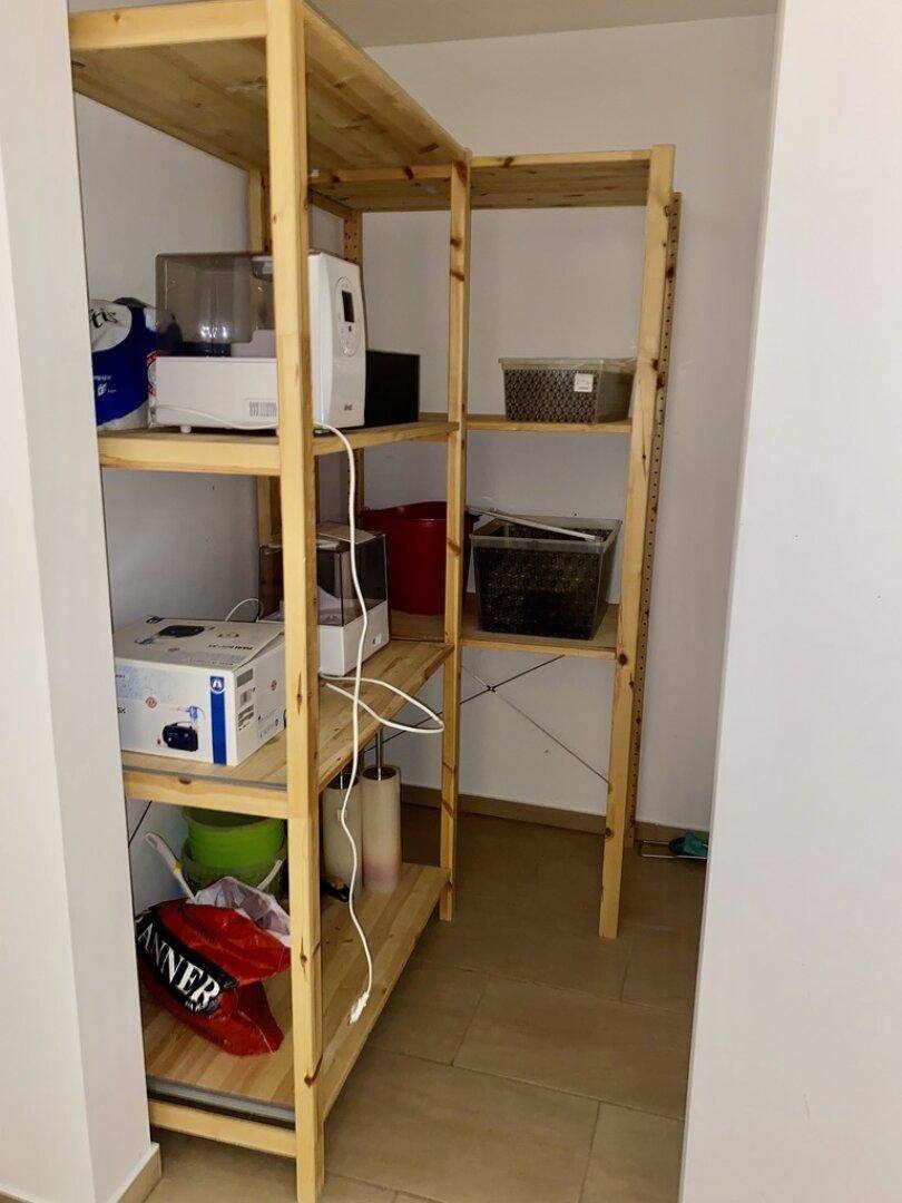 Praktischer Abstellraum mit offenen Holzregalen für zusätzliche Lagerfläche.